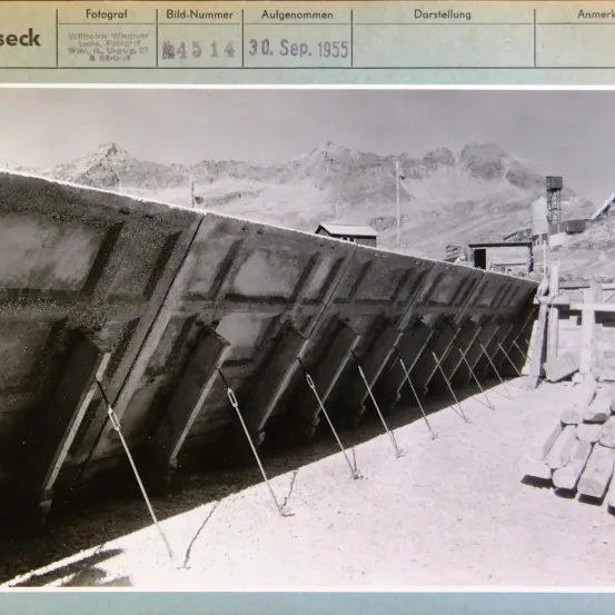 Ein Foto zeigt eine große Betonstruktur mit einem Gittermuster und einer Bergkette im Hintergrund. Das Foto wurde am 30. September 1955 aufgenommen und ist mit dem Namen des Fotografen und dem Datum versehen.
