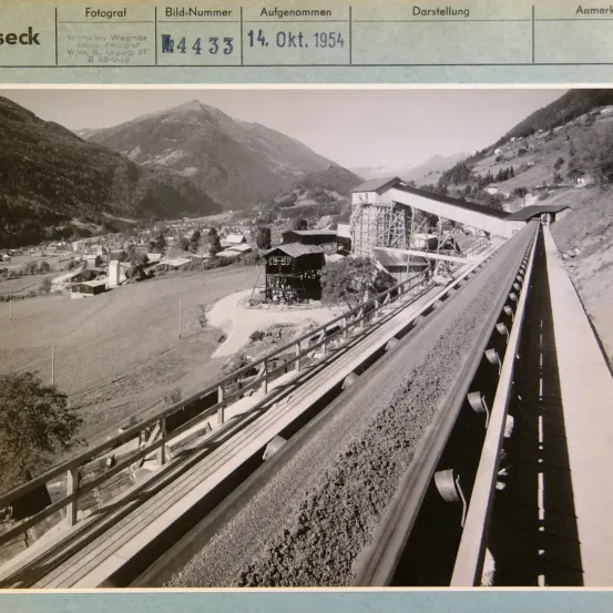 Schwarz-Weiß-Foto mit der Bezeichnung 'seck' vom 14. Okt. 1954, das ein Gebirgsgebiet mit einer Straße, einer Brücke, einem Gebäude und einem Förderband zeigt.