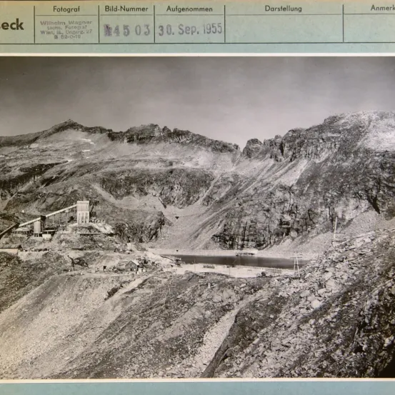 Ein Foto von 1955 zeigt eine Berglandschaft mit einer kleinen Siedlung und einer Baustelle. Es enthält Details wie Fotograf Wilhelm Wagner, Ort Wien und Bildnummer N4503.