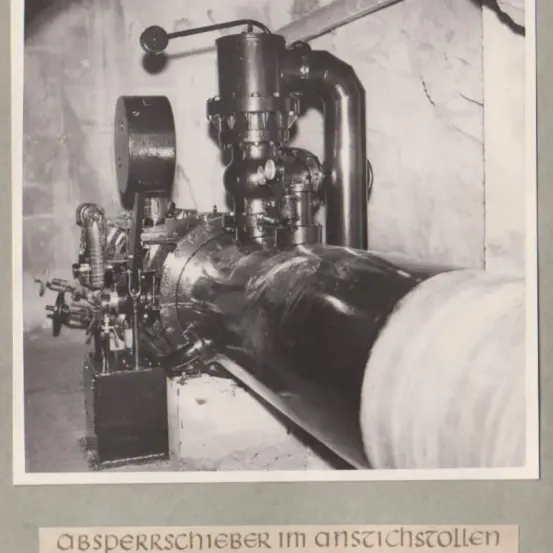 Ein Schwarz-Weiß-Bild zeigt ein industrielles Gerät mit Rohren und einem großen zylindrischen Rohr. Das Gerät ist auf einem Betonfundament montiert. Die Bildunterschrift lautet 'Absperrschieber im ansichtsollen'.