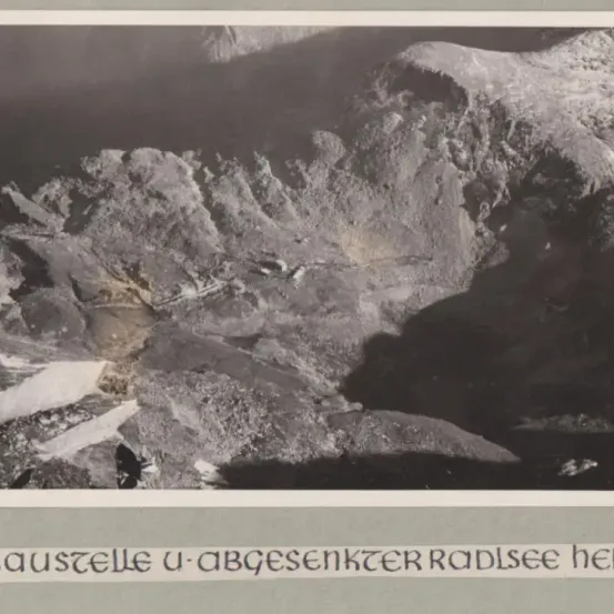 Ein Schwarz-Weiß-Bild zeigt raues Berggelände mit steilen Klippen und einem Tal darunter. Die von den Bergen geworfenen Schatten erzeugen einen dramatischen Effekt.