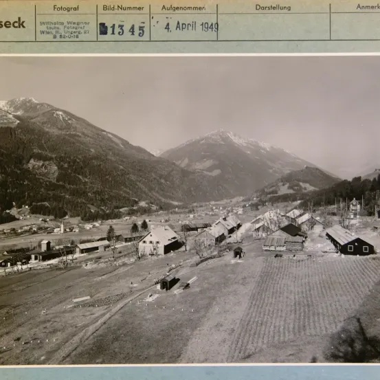Ein Foto vom 4. April 1949 zeigt ein Dorf eingebettet zwischen Bergen. Das Bild zeigt Häuser, eine Kirche und Felder. Bildnummer 1345 wurde von Wilhelm Wagner aufgenommen.