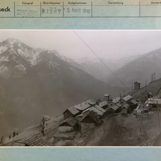 Schwarz-Weiß-Foto vom 5. April 1949, das eine Berglandschaft mit mehreren kleinen Gebäuden und einem Versorgungsmast zeigt.