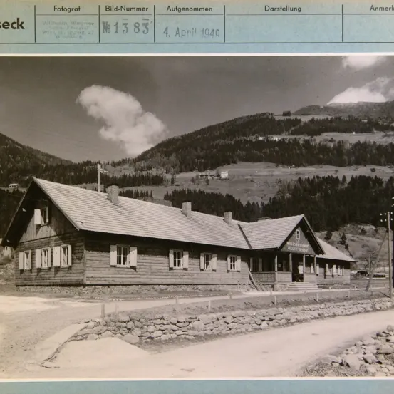 Schwarz-Weiß-Foto eines Gebäudes mit der Bezeichnung 'M 1383' und einem Datum vom 4. April 1949. Das Gebäude ist aus Holz mit mehreren Fenstern und Schornsteinen.