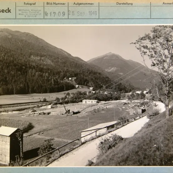 Schwarz-Weiß-Foto mit der Aufschrift 'Fotograf Wilhelm Wagner, Wien III, Ungargasse 27, B 82-0-18.' Es zeigt eine Berglandschaft mit einem Weg, der zu einem kleinen Gebäude führt. Das Datum 26. Sep. 1949 ist ebenfalls sichtbar.