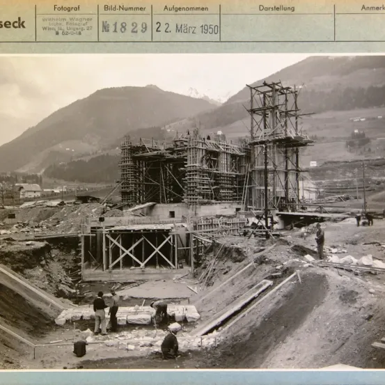 Ein Schwarz-Weiß-Foto einer Baustelle mit Arbeitern, datiert auf den 2. März 1950. Es enthält eine Tabelle mit Details wie Fotograf, Fotonummer, Datum und Beschreibung.