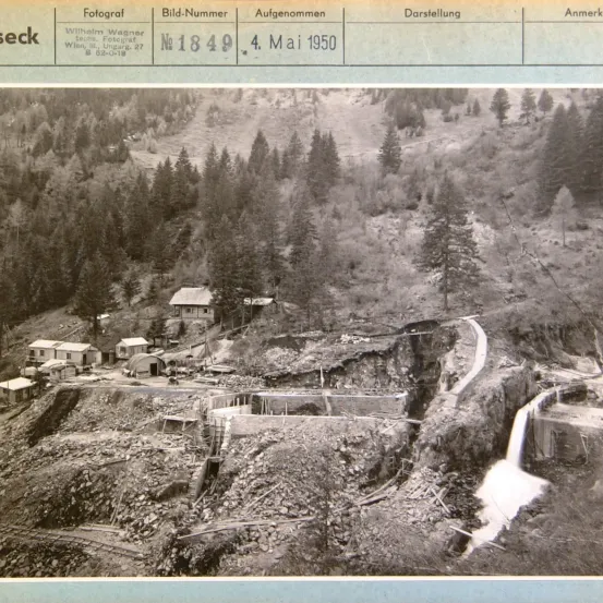 Schwarz-Weiß-Bild einer bergigen Gegend mit einem Wasserfall. Mehrere Gebäude sind am Berghang sichtbar, einschließlich eines kleinen Hauses. Das Foto ist mit dem Datum 4. Mai 1950 versehen.
