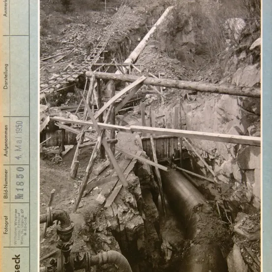 Schwarz-Weiß-Foto von 1950, das einen Tunnel mit eingestürzten Wänden, zerbrochenen Bahngleisen und verstreuten Holzbalken zeigt.