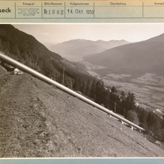 Ein Foto zeigt eine lange Pipeline an einem Hang mit einer Gebirgslandschaft im Hintergrund. Das Foto ist vom 14. Oktober 1950 und ist mit der Bildnummer 1982 gekennzeichnet.