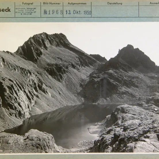 Ein Schwarz-Weiß-Foto zeigt raues Berggelände mit einem Gewässer. Die Metadaten enthalten 'Fotograf', 'Bild-Nummer', 'Aufgenommen' und 'Darstellung', mit dem Datum 13. Okt. 1950.