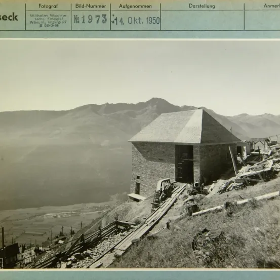 Ein Schwarz-Weiß-Bild zeigt eine Berglandschaft mit einem kleinen Haus im Vordergrund, datiert auf den 14. Oktober 1950. Das Bild enthält Details wie Fotografenname, Bildnummer und Beschriftung.