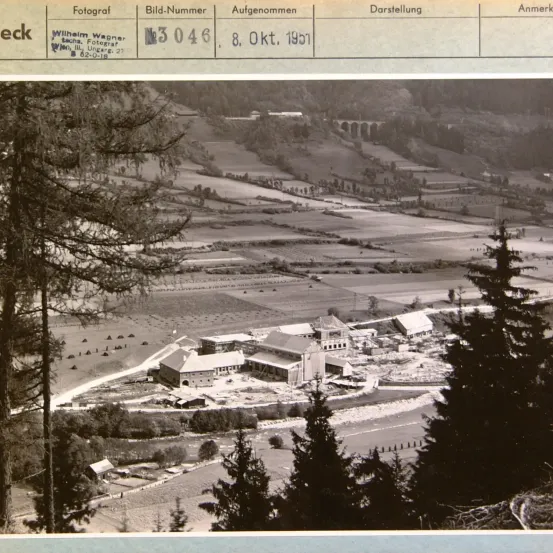Eine Schwarz-Weiß-Fotografie von 1951 mit einer Luftaufnahme eines Dorfes mit Feldern und einer Brücke. Der Fotograf ist Wilhelm Wagner.
