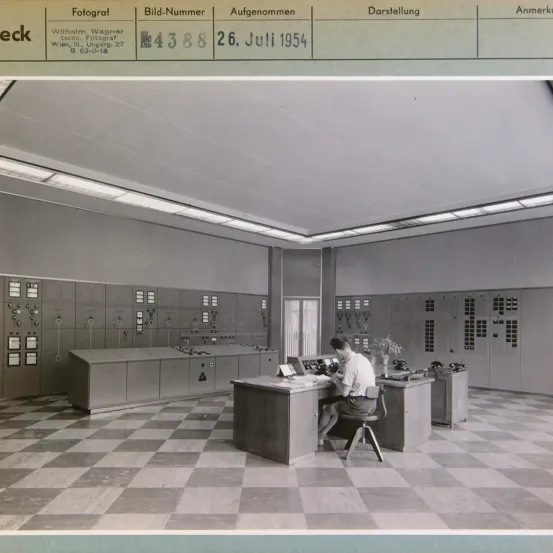 Eine Schwarz-Weiß-Fotografie des Inneren mit einem Mann, der am Schreibtisch sitzt, aufgenommen am 26. Juli 1954 von Wilhelm Wagner.