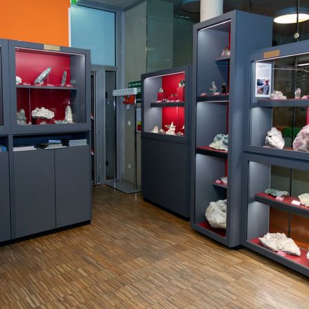 Ein Innenraum mit einer Sammlung von Mineralien in einem grauen Schrank mit roten Regalen.