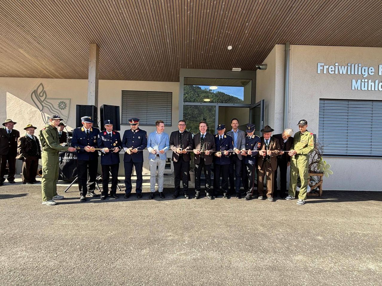 Eine Gruppe von Militärangehörigen und Offiziellen steht in einer Reihe und hält ein Band, möglicherweise für eine Eröffnungszeremonie.