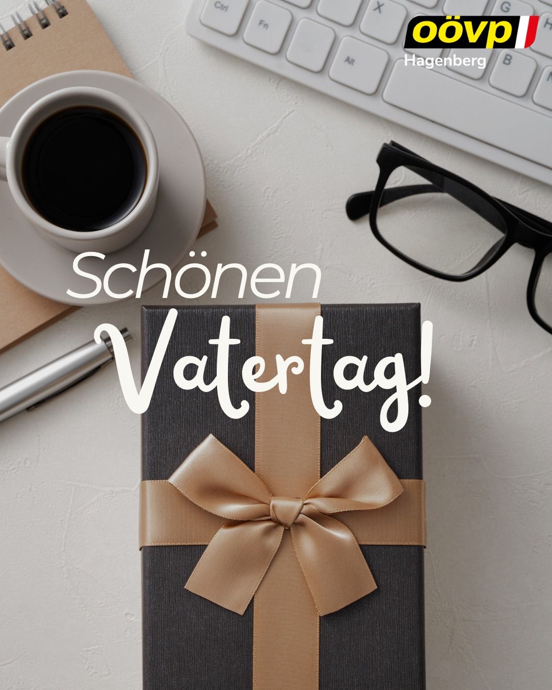 Ein Geschenkkarton mit Schleife steht auf einem Schreibtisch, mit einer Tasse Kaffee, einem Stift und einer Brille. Der Text lautet 'Schönen Vatertag!'