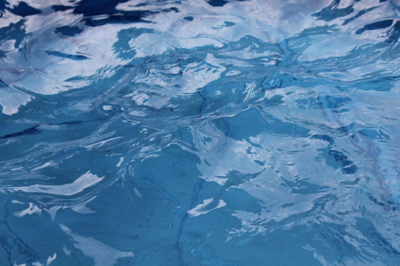 Eine Nahaufnahme eines Pools mit blauem Wasser, das Wellen und Reflexionen zeigt. Das Wasser erscheint sauber und klar.