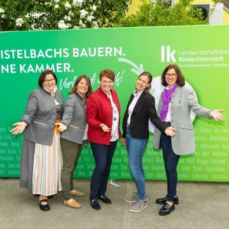 Fünf Frauen stehen vor einem grünen Schild, auf dem 'Mistelbachs Bauern. Eine Kammer.' steht. Sie lächeln und posieren für ein Foto.