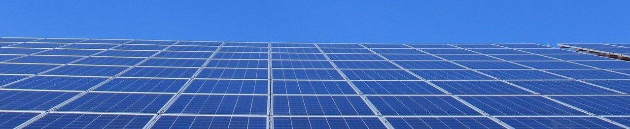 Eine große Solarpanel-Anlage im Freien unter einem klaren blauen Himmel, die Sonnenlicht zur Energieumwandlung einfängt.