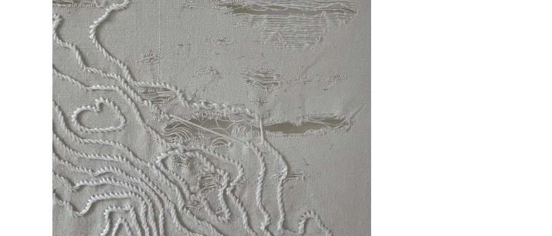 Das Bild zeigt ein Kunstwerk aus gestickten weißen Fäden auf grauem Hintergrund. Die Fäden bilden komplizierte Muster, die an Karten erinnern und abstrakte Darstellungen von Landschaften erzeugen.