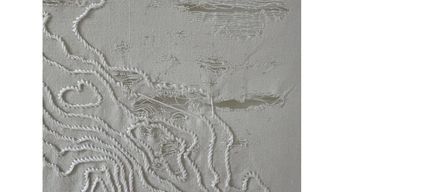 Das Bild zeigt ein Kunstwerk aus gestickten weißen Fäden auf grauem Hintergrund. Die Fäden bilden komplizierte Muster, die an Karten erinnern und abstrakte Darstellungen von Landschaften erzeugen.