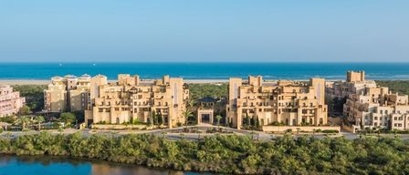 Luftaufnahme eines Hotelkomplexes mit mehreren Gebäuden, umgeben von viel Grün und mit Blick auf das Meer.