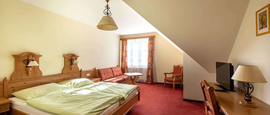 Ein gemütliches Schlafzimmer mit einem Holzbett, einer Couch und einem Fenster mit Vorhängen.