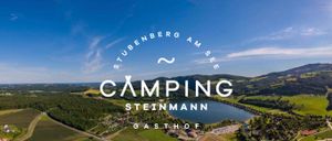 Eine Luftaufnahme eines Sees mit Bergen und Feldern, blauer Himmel mit Wolken. Die Worte 'Camping Steinmann Gasthof' sind in Weiß auf einem weißen Hintergrund geschrieben.