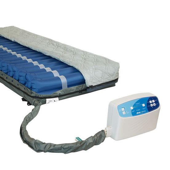 Ein blaues Luftmatratze mit Luftzellen und einer angeschlossenen Pumpe wird angezeigt. Die Matratze hat eine graue Basis und eine weiße Abdeckung. Die Pumpe hat ein blaues und weißes Etikett.