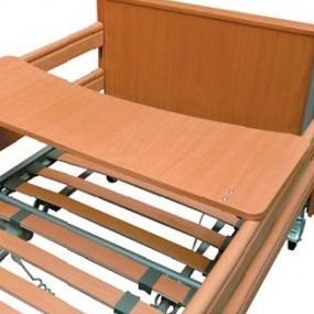 Ein Nahaufnahme einer Krankenhausbett mit einem hölzernen Kopfteil, einem klappbaren Tisch und einem Metallgriff. Das Bett hat einen Metallrahmen.