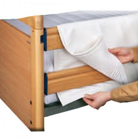 Eine Person passt eine weiße Bettdecke unter einem hölzernen Etagenbett an. Die Person trägt einen braunen Pullover. Die Bettdecke hat einen blauen Streifen am Rand.