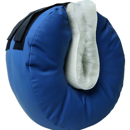 Ein blaues Kissen mit weißer Schaffell-Fütterung, befestigt durch einen schwarzen Riemen. Es ist kreisförmig mit einem Loch in der Mitte.