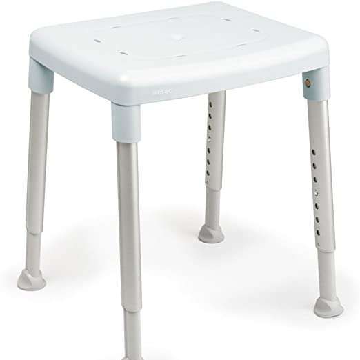Ein weißer Plastikhocker mit vier verstellbaren Beinen und einem perforierten Sitz. Der Hocker ist für die Nutzung in der Dusche konzipiert und bietet eine sichere und bequeme Sitzmöglichkeit.