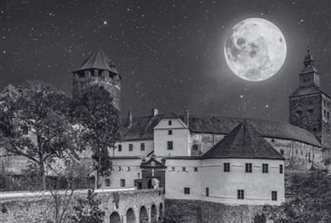 Ein Schwarz-Weiß-Foto einer mittelalterlichen Burg unter einem Vollmond, mit Sternen und einem Turm im Hintergrund.