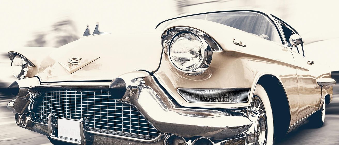 Ein Oldtimer Cadillac Eldorado mit polierter Chrom-Kühlermaske und Scheinwerfer fährt die Straße hinunter. Das Auto ist in Bewegung, ein Bewegungsunschärfe-Effekt.