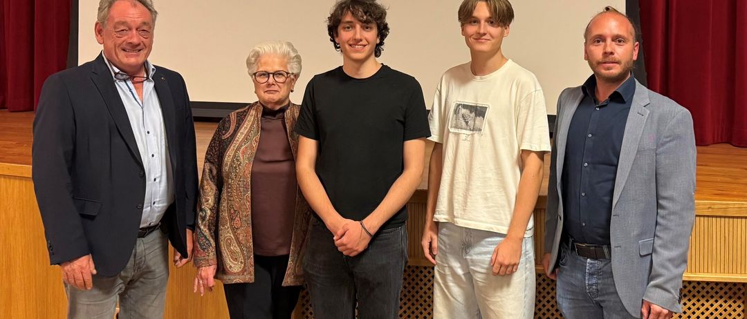 Fünf Personen stehen vor einer Leinwand mit einem Tunnelbild. Sie scheinen bei einer Präsentation oder Veranstaltung zu sein.