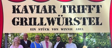 Plakat für eine Aufführung des Theaterstücks Grillwurstel mit einer Gruppe von Menschen auf einer Bank, Aufführungsdaten und Ticketinformationen.