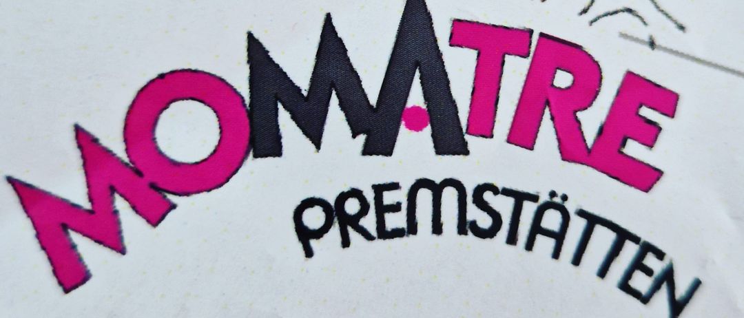 Ein Nahaufnahme eines weißen Etiketts mit dem Wort Momatre in Pink und Schwarz gedruckt, vor einem rosa Hintergrund.