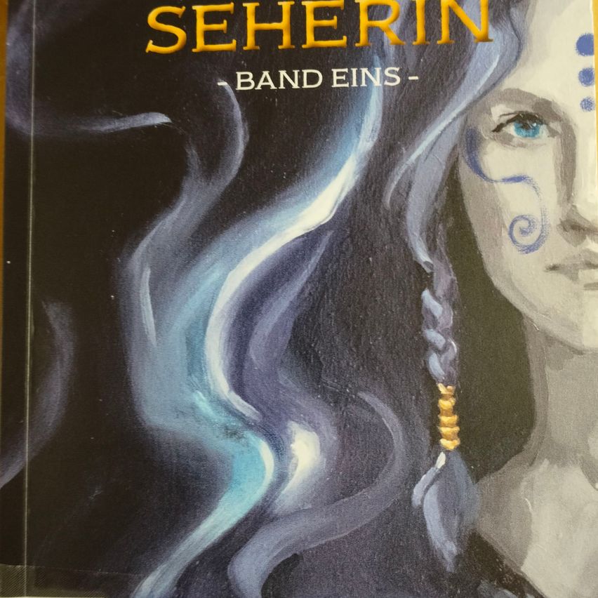 The cover of a book titled 'Seherin'. It features a woman with long braided hair, blue eyes, and a face painted with blue dots and swirls. The background is dark.