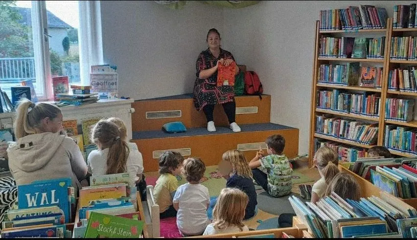 Eine Frau liest ein Buch für eine Gruppe von Kindern in einer Bibliothek.