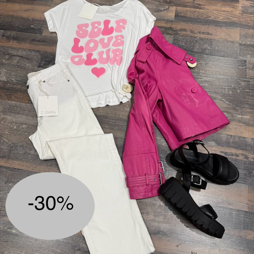 Ein weißes T-Shirt mit pinkem Text, weiße Jeans, eine rosa Lederjacke, schwarze Sandalen und ein Rabattsticker mit -30% auf einem Holzboden.