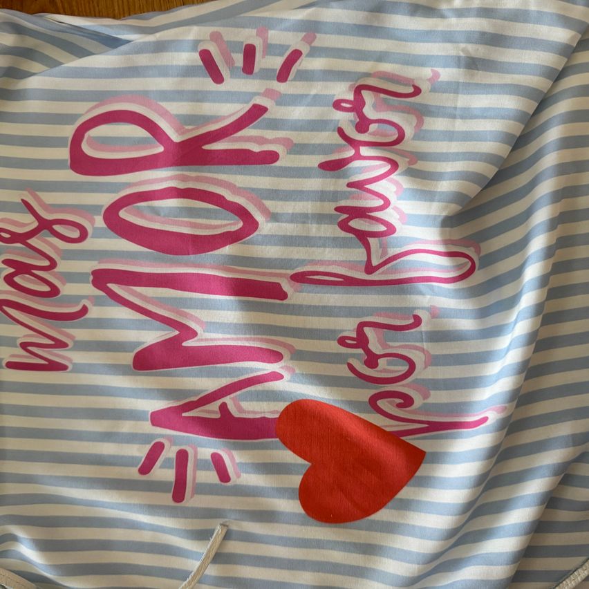 Ein blau-weiß gestreifter Stoff mit 'MAMA' und 'BESTE TOCHTER ALLER ZEIT' in Pink, mit einem roten Herz in der Mitte.