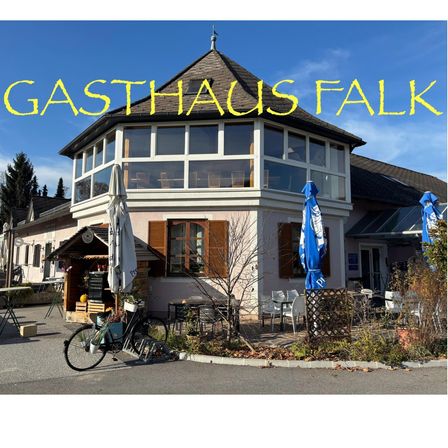 Ein Restaurant namens Gasthaus Falk mit einem Fahrrad davor, blauen Sonnenschirmen und einer verglasten Veranda.