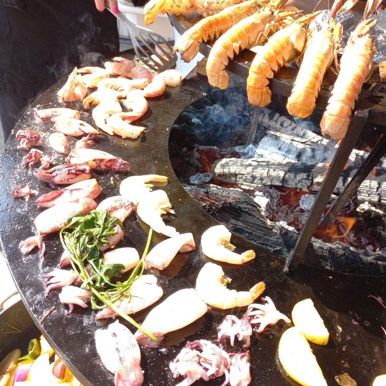 Ein Grill mit verschiedenen Meeresfrüchten darauf. Garnelen, Hummer und andere Meerestiere sind gegrillt und auf dem Grill platziert.