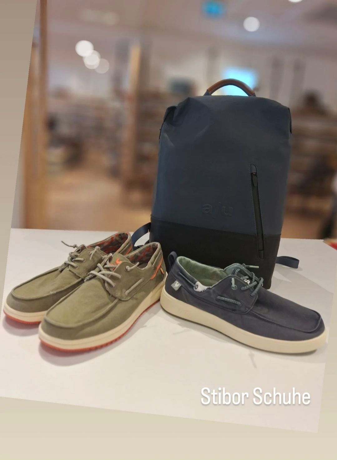 Ein Paar lässige Schuhe in Olivgrün und Marineblau mit weißen Sohlen und einem Rucksack mit dem Text 'alu' auf einer weißen Oberfläche.