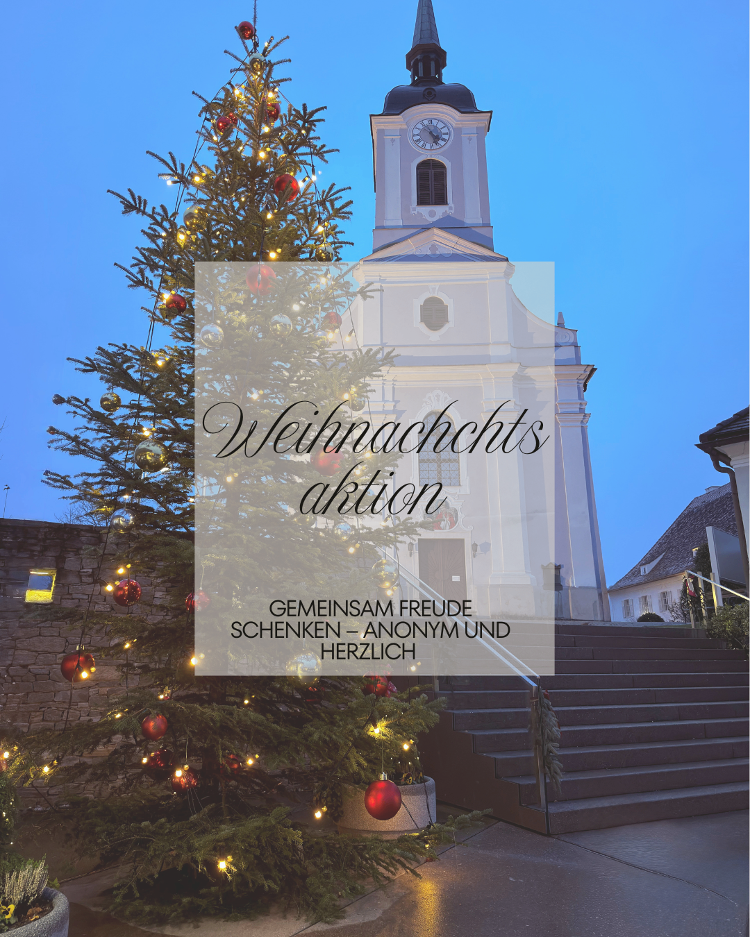 Ein Weihnachtsbaum steht vor einer Kirche. Der Baum ist mit Lichtern und Ornamenten geschmückt. Die Kirche hat einen Turm mit einer Uhr und einem Dachreiter.