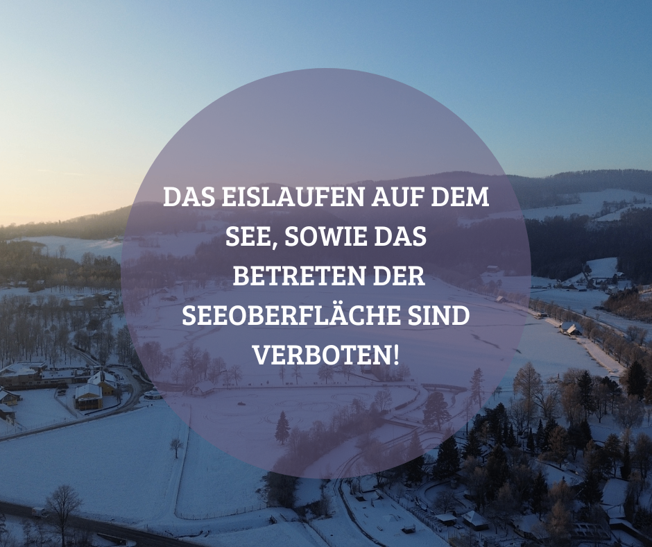 Eine verschneite Landschaft mit einem Haus und Bergen im Hintergrund. Ein Textüberlagerung verbietet das Eislaufen und das Betreten der Seeoberfläche.