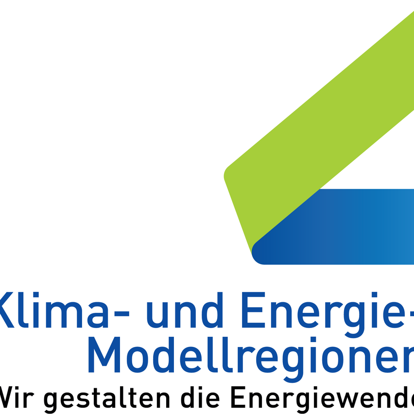 Das Bild zeigt das Logo für 'Klima- und Energie-Modellregionen'. Das Logo besteht aus einem blau-grünen Rechteck mit schrägen Kanten auf weißem Hintergrund. Der Text ist fett und blau.