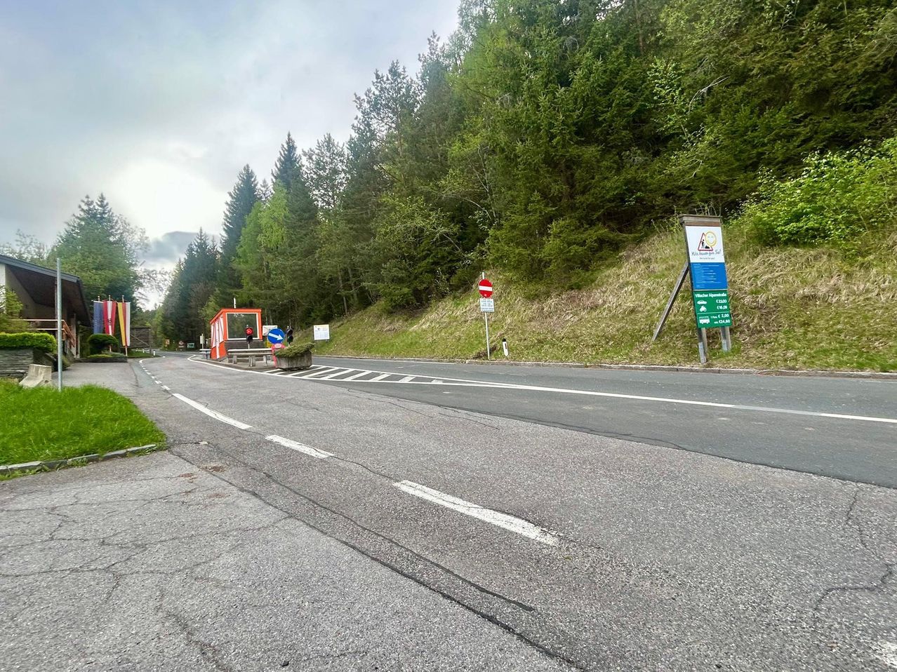 Eine Straße in einem bewaldeten Gebiet mit weißen Markierungen auf der Straße und Bäumen und Bergen in der Ferne.