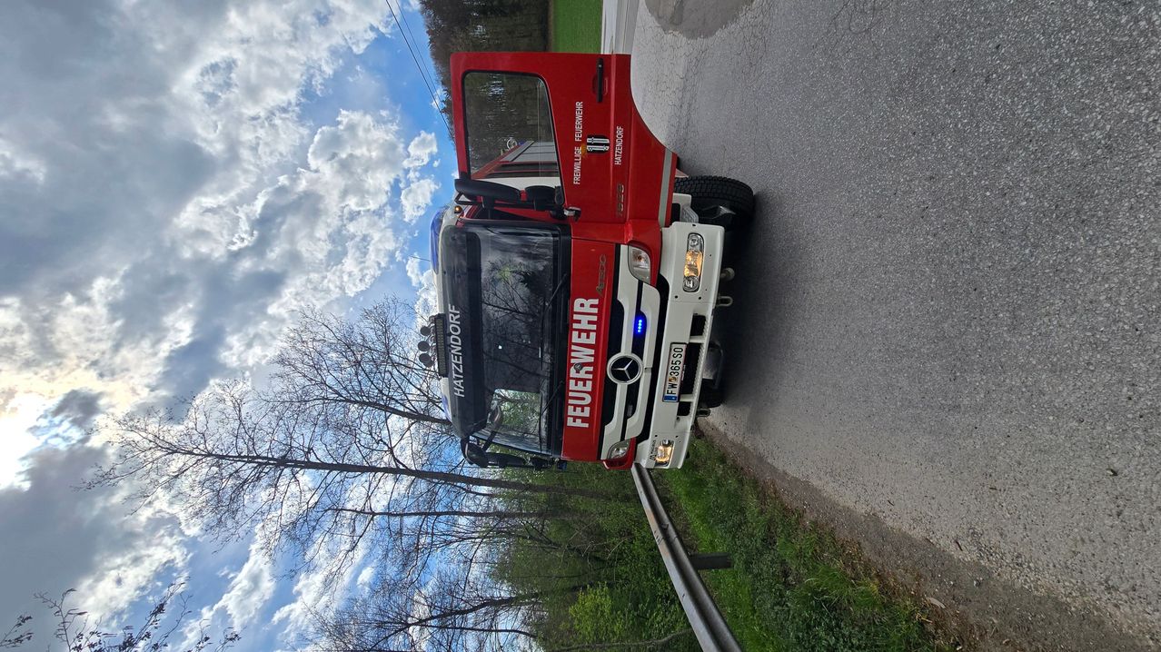 Ein roter Feuerwehrwagen mit dem Wort Feuerwehr an der Seite ist am Straßenrand geparkt.